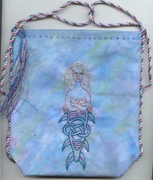 Hand dyed blue bag with purple and green, celtic mermaid embroidered with metallic floss on front of bag.